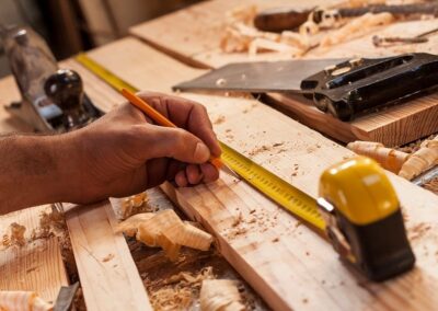 carpenter working with tape measure on board with wood shavings