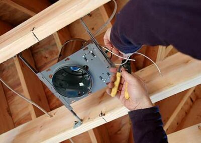 Electrician connecting can lighting to wooden floor joists